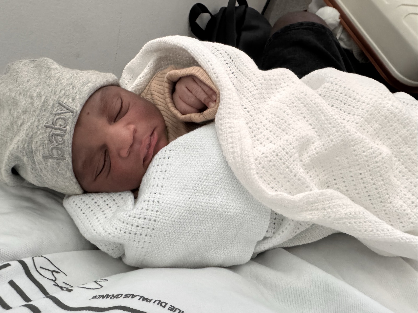 Baby Shokunbi sleeping peacefully, wrapped in a white blanket